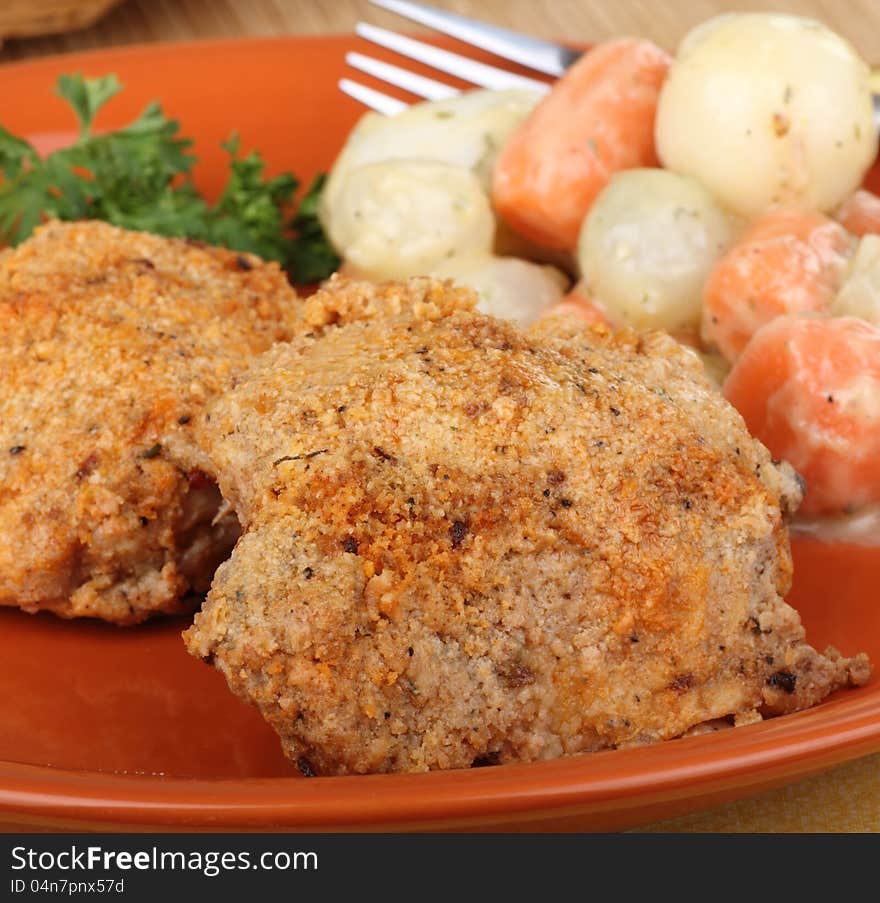 Baked breaded chicken thighs with vegetables on a dinner plate. Baked breaded chicken thighs with vegetables on a dinner plate