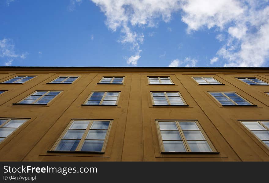 Yellow house facade with blue sky reflection in windows. Yellow house facade with blue sky reflection in windows