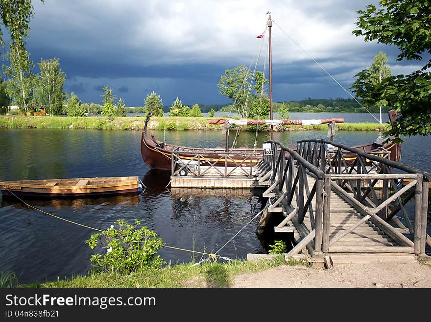 Retro wooden boats near a wooden pier on the river before a thunderstorm. Retro wooden boats near a wooden pier on the river before a thunderstorm