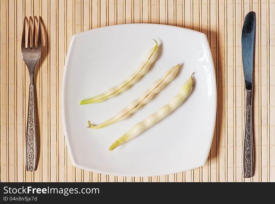 Three pods of beans on a white plate.