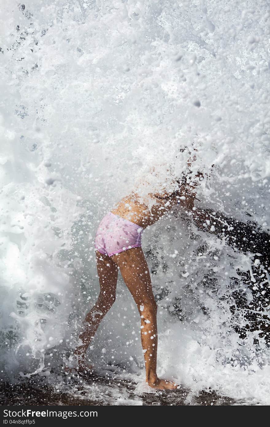 Sea waves breaks over a young girl