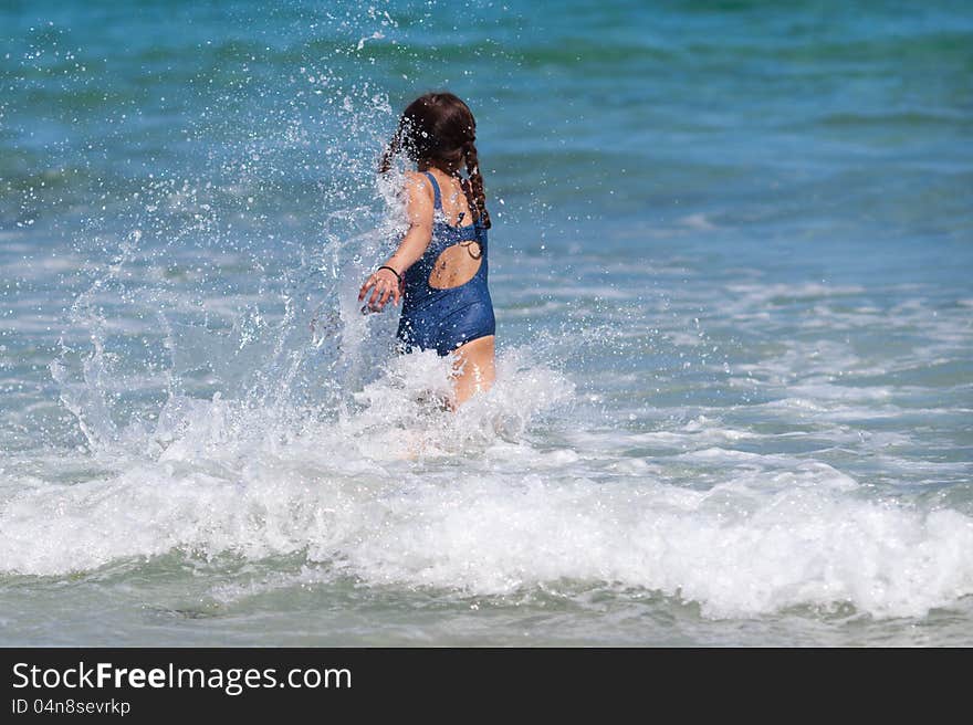 Young girl runs in the wave