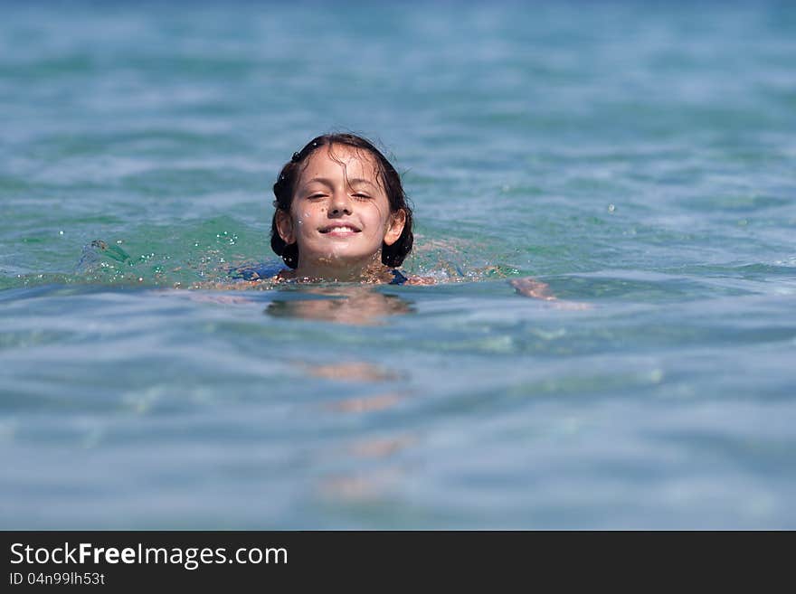 Pretty and smiling girl swims in the sea water