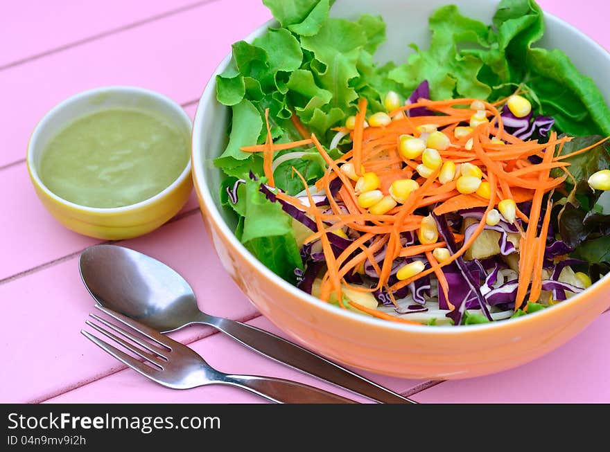 Colorful of vegetables salad with spoon on pink table