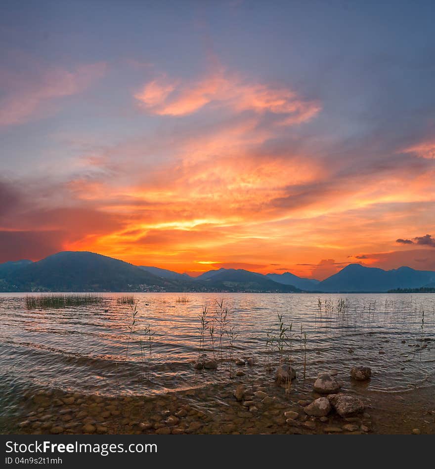 Colorful sunrise on Lake with majestic clouds, Alpes mountains on background