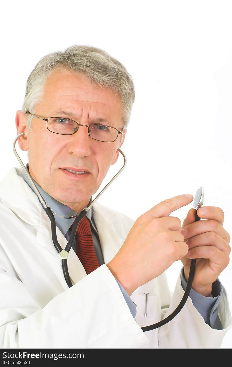 Vertical portrait of matured, graying doctor with stethoscope on his neck. His eyes attendive but cheerful. He wears a physician’s white coat, a blue shirt an a red tie. His forefinger indicates the ending of a stethoscope. Vertical portrait of matured, graying doctor with stethoscope on his neck. His eyes attendive but cheerful. He wears a physician’s white coat, a blue shirt an a red tie. His forefinger indicates the ending of a stethoscope.