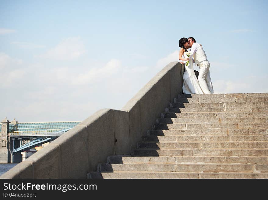 Romantic bride and groom at wedding walk on staircase of embankment