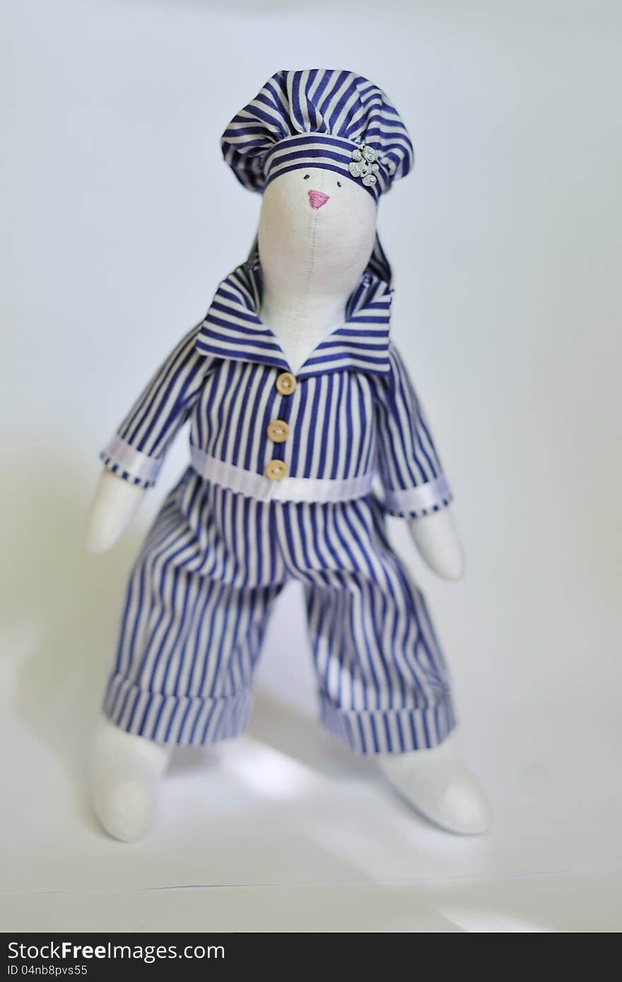 The doll a tilde hare in a striped suit sits. The doll a tilde hare in a striped suit sits