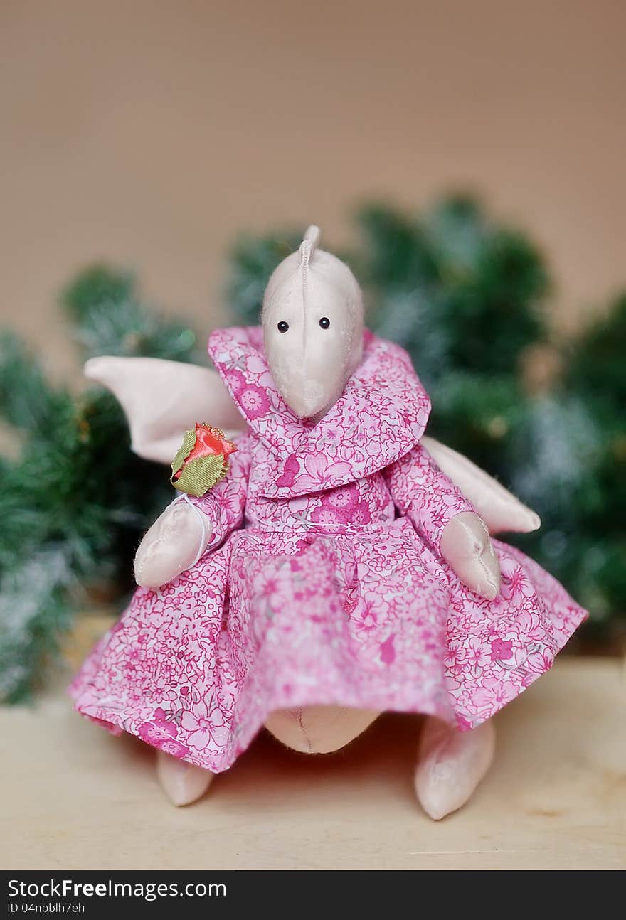 Toy a dragon the girl in a pink dress under a fir-tree. Toy a dragon the girl in a pink dress under a fir-tree