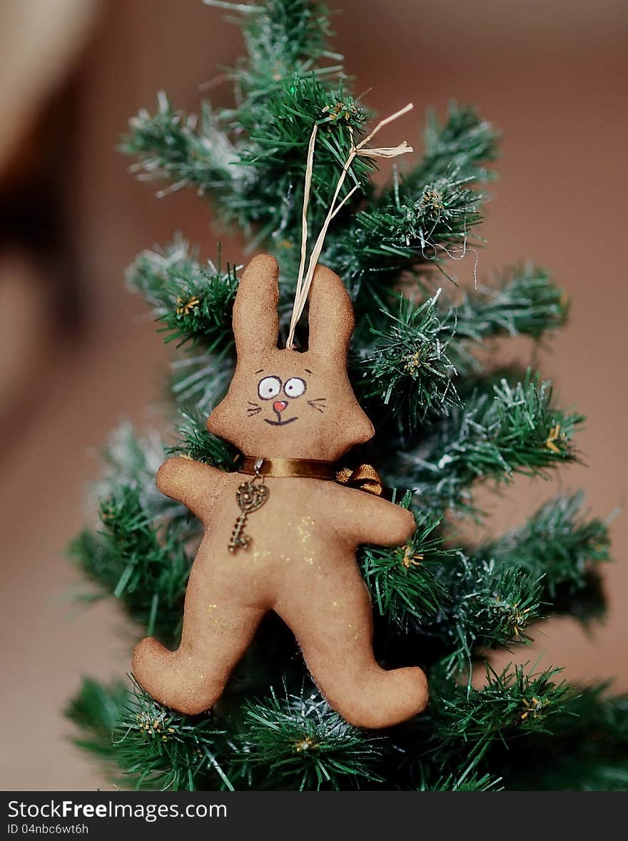 The toy brown hare hangs on a green fir-tree. The toy brown hare hangs on a green fir-tree