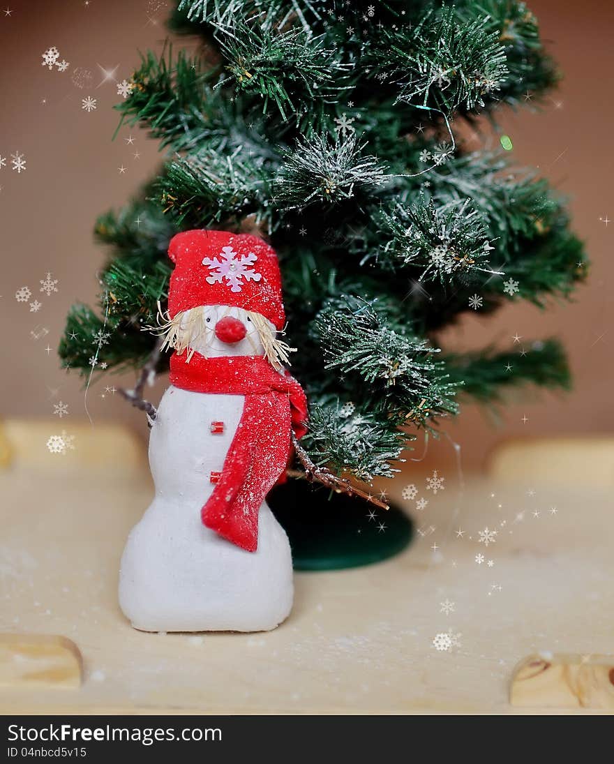 Toy angel a snowman in a red cap under a fir-tree. Toy angel a snowman in a red cap under a fir-tree