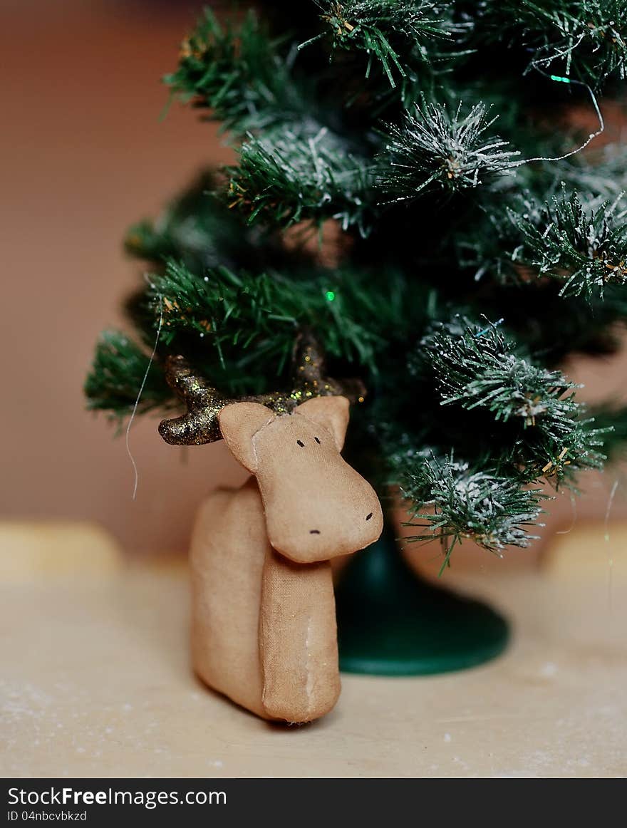 Handwork of a brown deer under a green fir-tree. Handwork of a brown deer under a green fir-tree