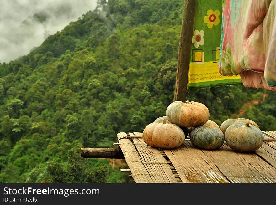 Pumpkin on the bamboo plank in hill tribe's house balcony with mountain background. Pumpkin on the bamboo plank in hill tribe's house balcony with mountain background