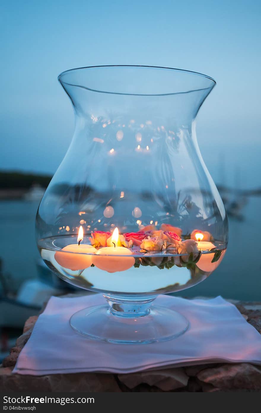 Round candles and rose peddles in a pot.