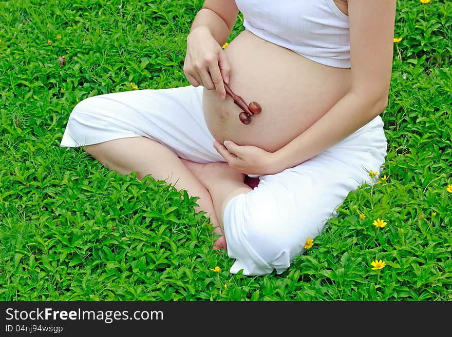 Pregnant mom with wooden massage in the garden with care