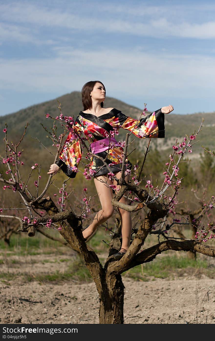 Girl in kimono on the tree and flowerses of the peach. Girl in kimono on the tree and flowerses of the peach