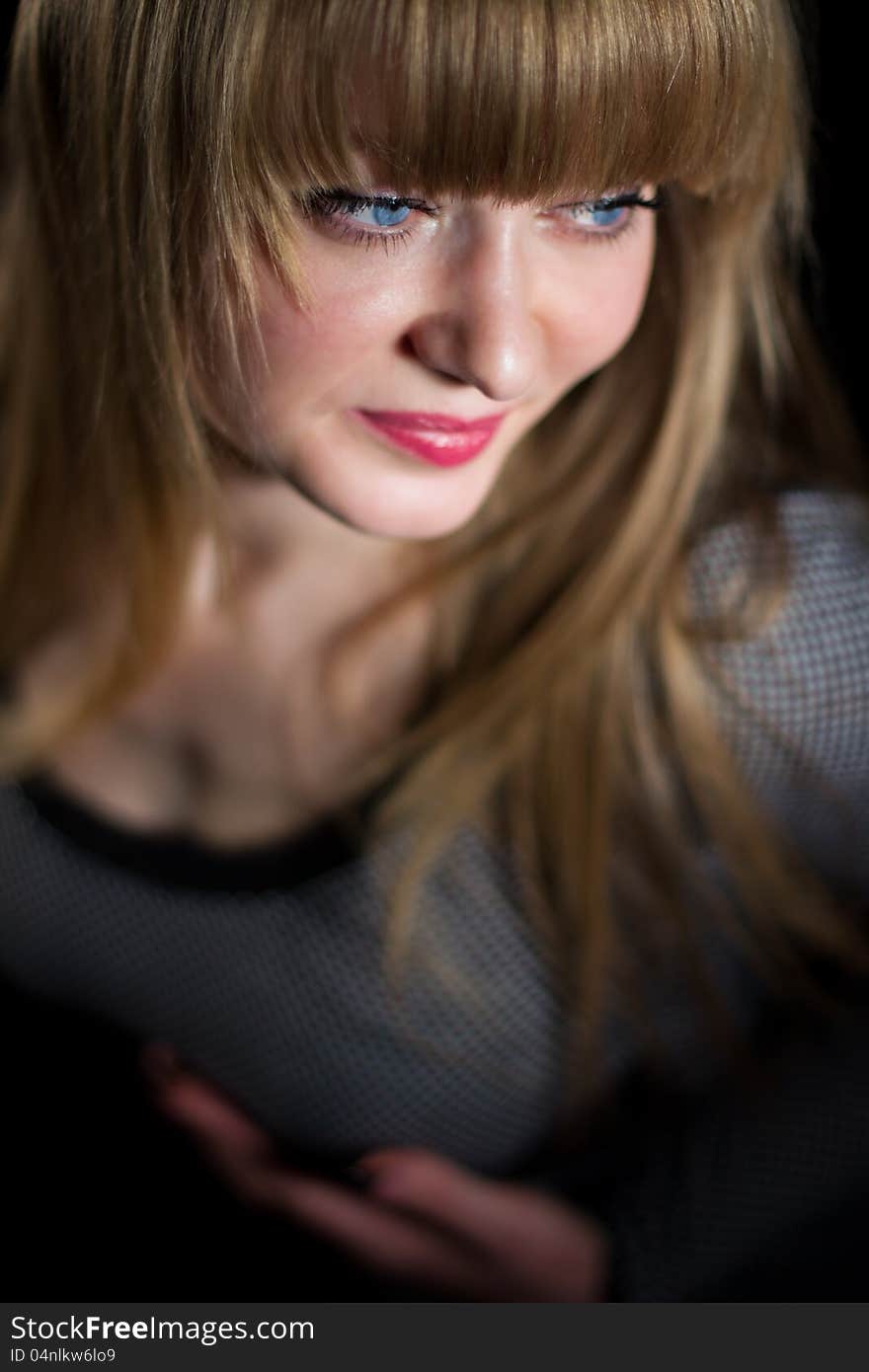 A girl with blue eyes in a dark dress on a dark background. A girl with blue eyes in a dark dress on a dark background