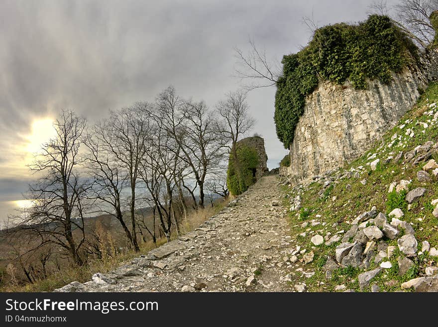 Ancient fortifications in the mountains in the rays of sunset. Genoese fortress