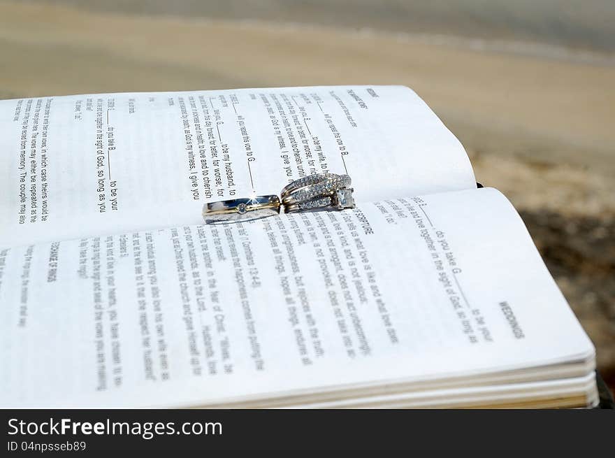 Just some wedding rings on a bible on a beach by the ocean