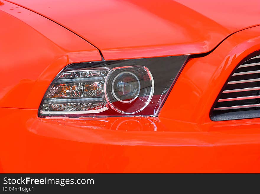 Head-light of a new, red, sport`s vehicle, closeup shot