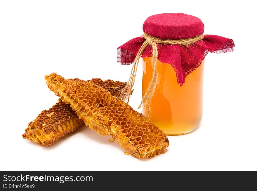 A jar of honey with honeycombs on a white background