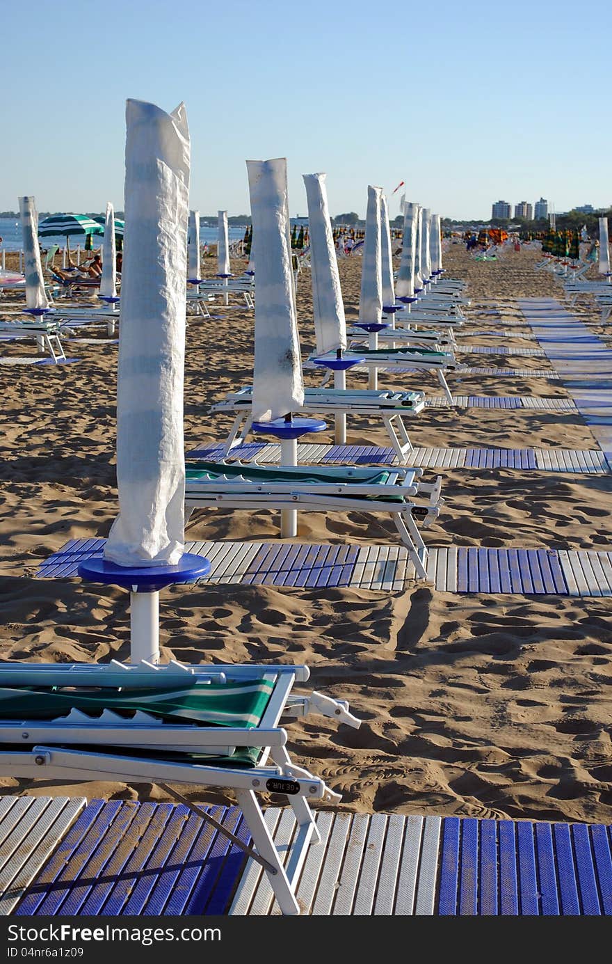 Beach umbrellas and sunbed over sand at the sunset