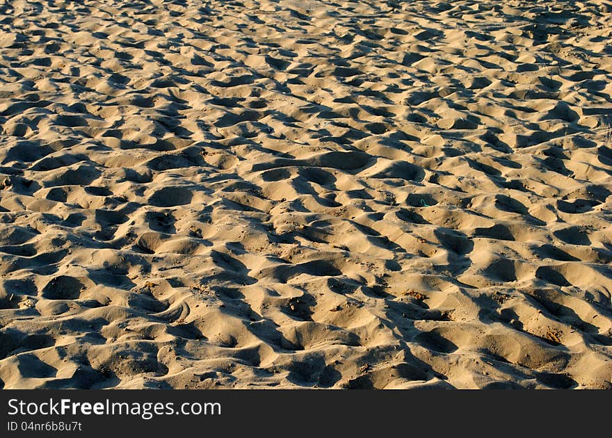 Sandy beach with sunset lights and shadows, as background