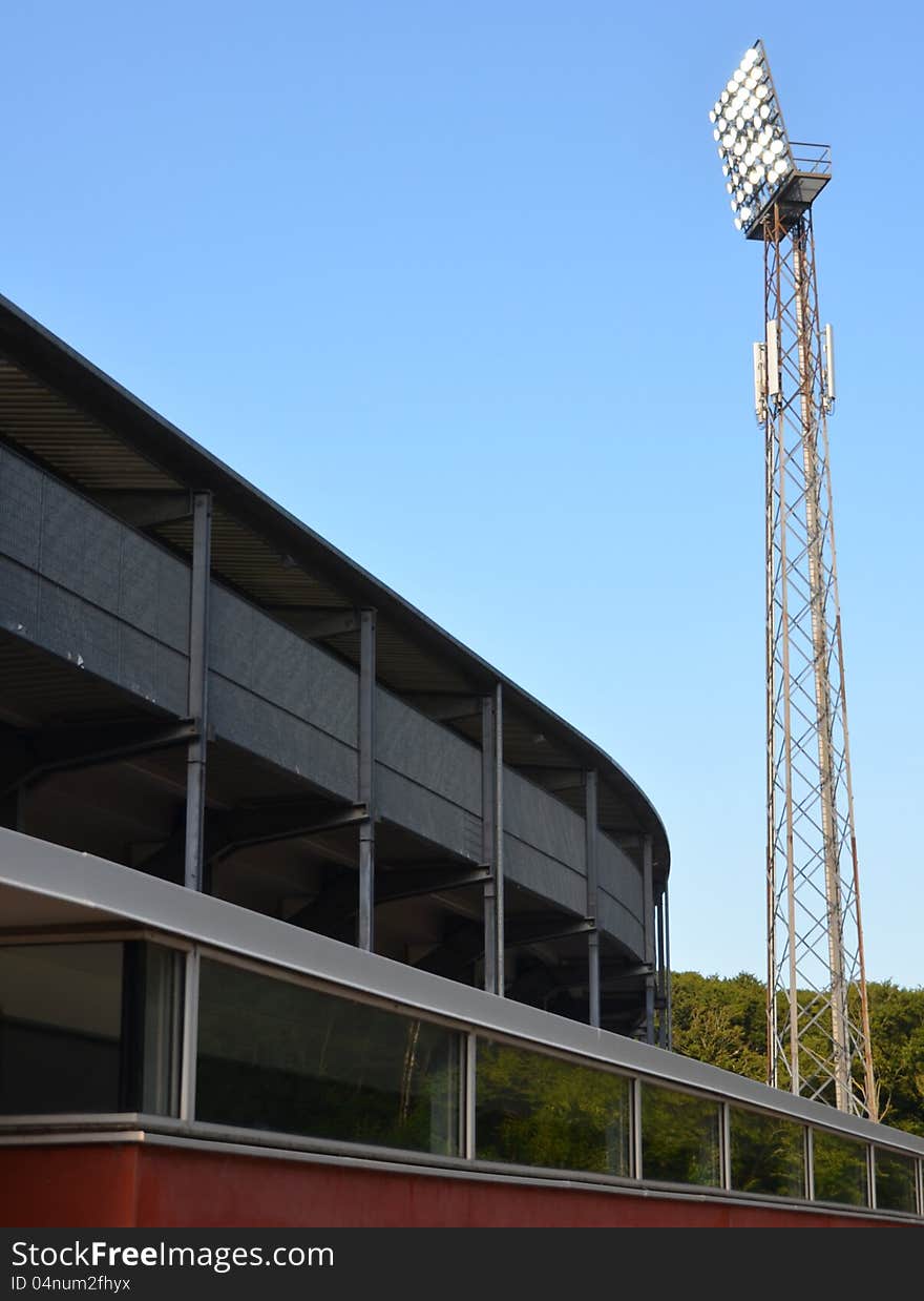 A turned-on light mast at stadium against the blue sky. A turned-on light mast at stadium against the blue sky