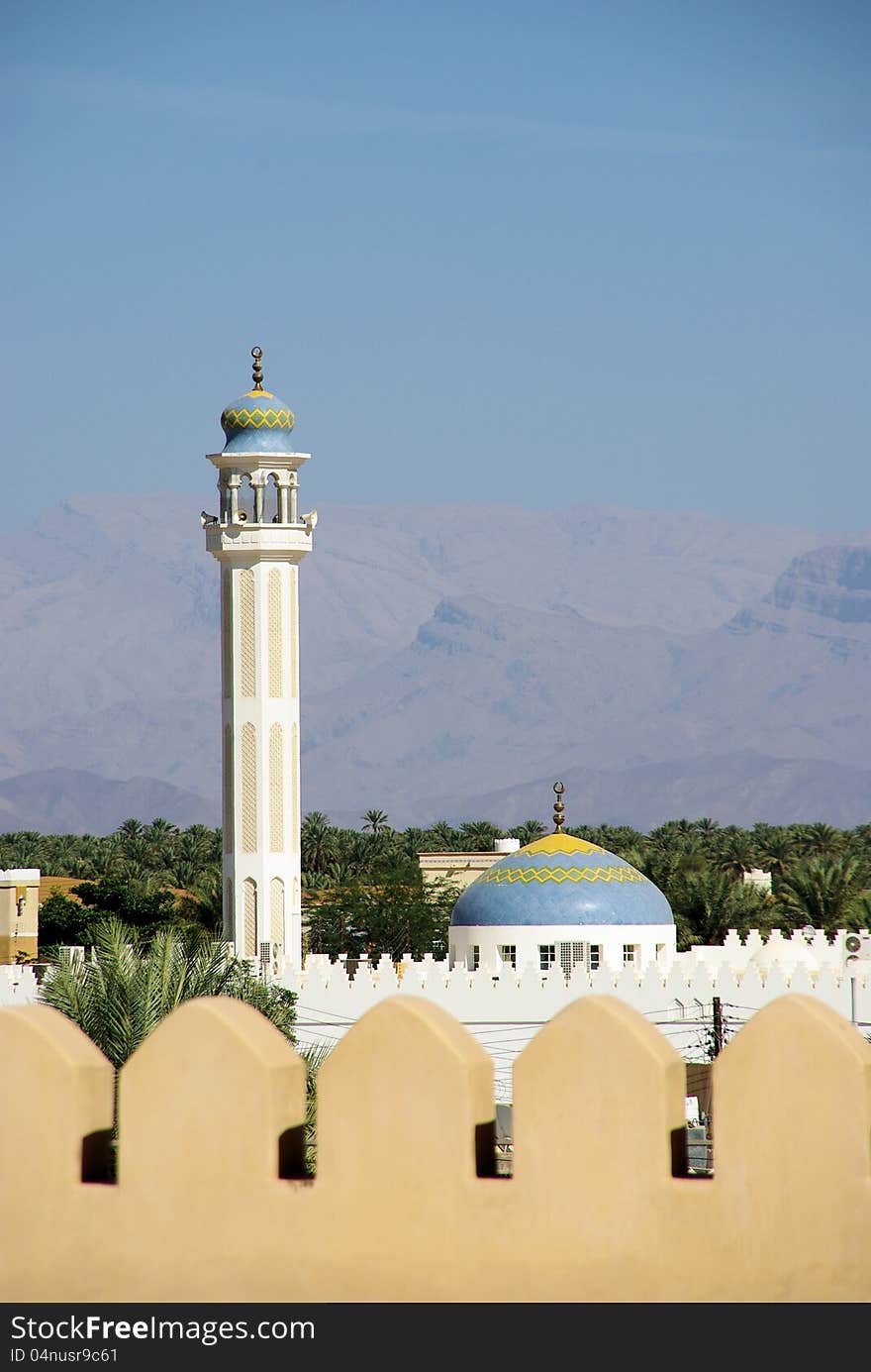 Omani landscape, mountains, mosque and palm trees.