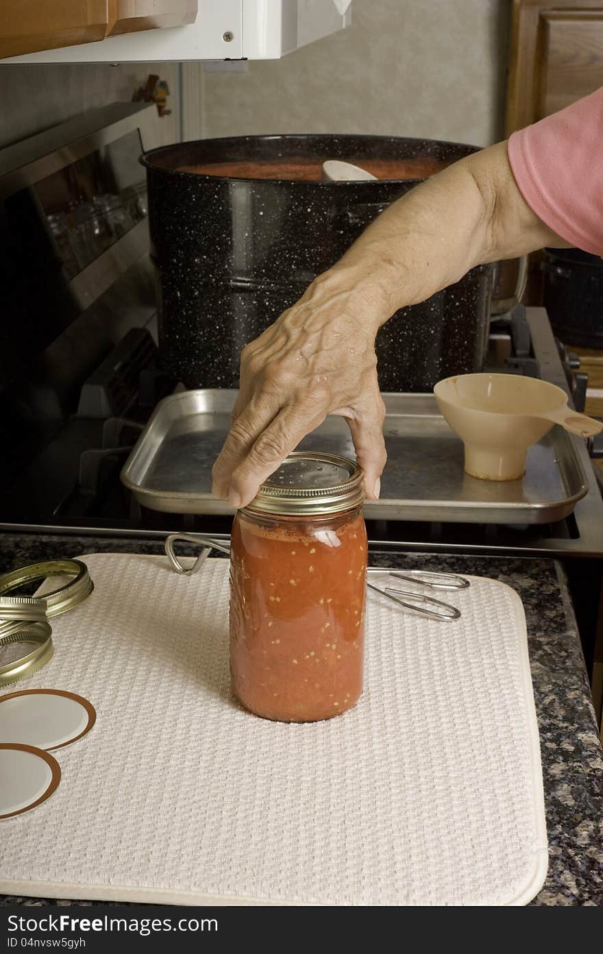 Placing Lid On Can Of Tomatoes.