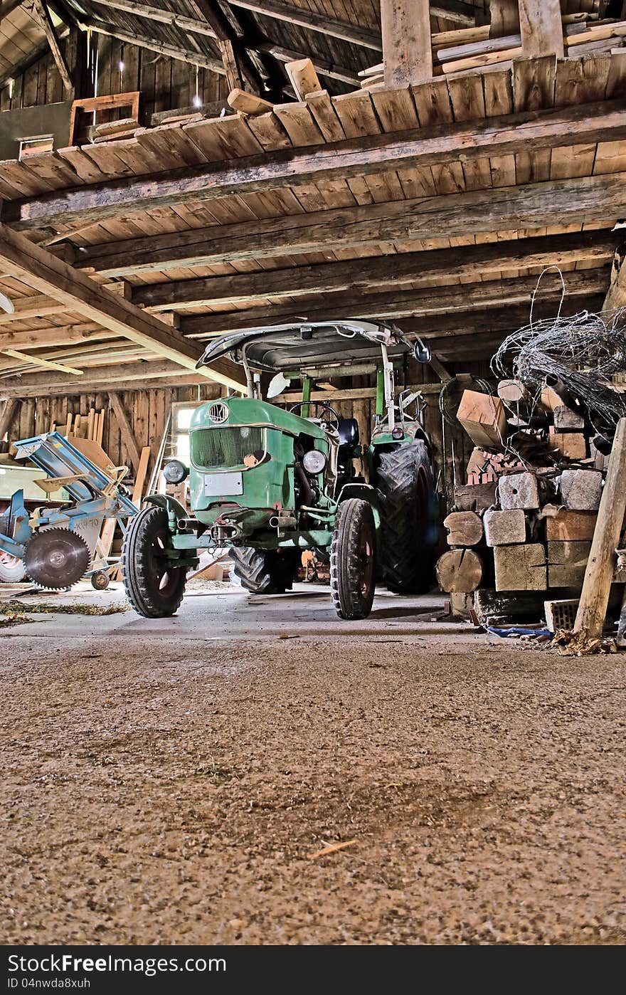 An old tractor standing inside an old barn