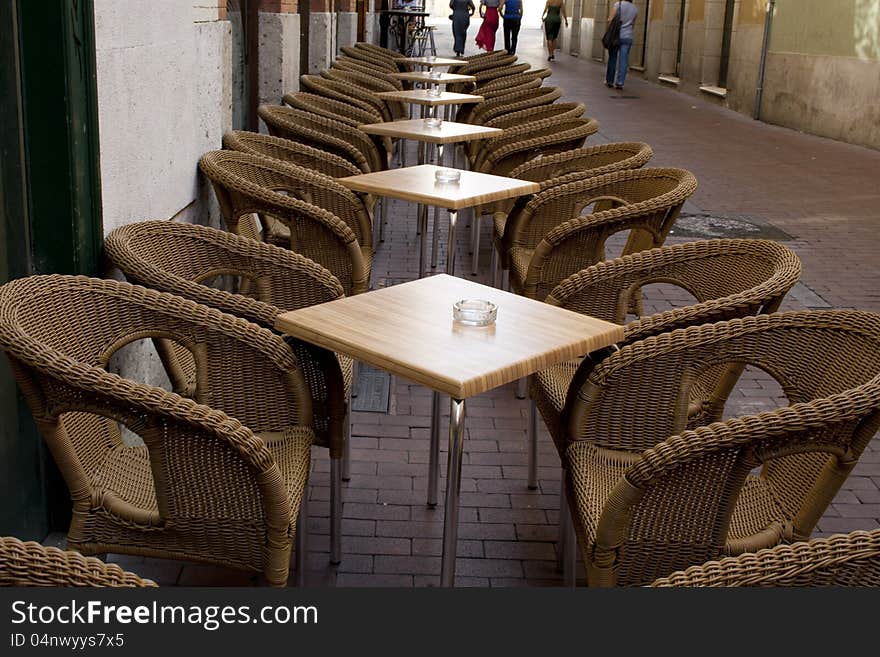 Tables and wicker chairs by bar in the street