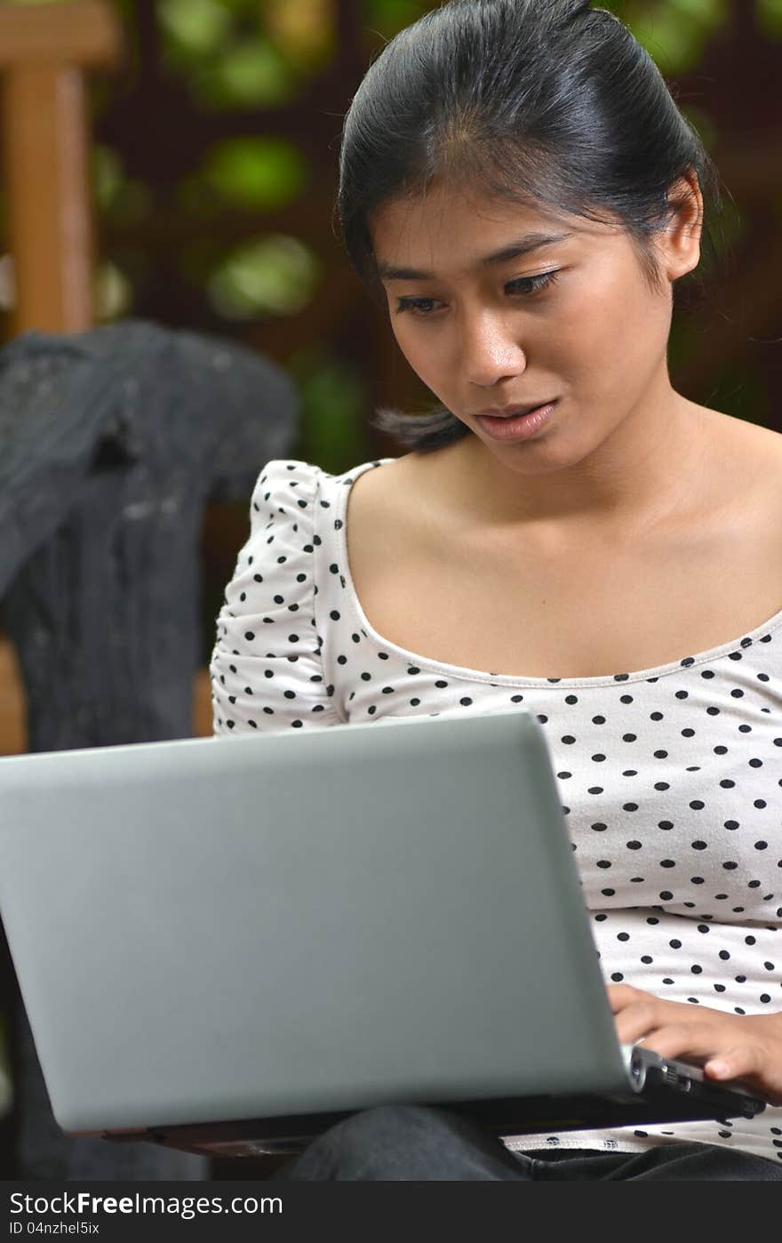 A young pretty southeast asian girls using a laptop at outdoor scene. A young pretty southeast asian girls using a laptop at outdoor scene