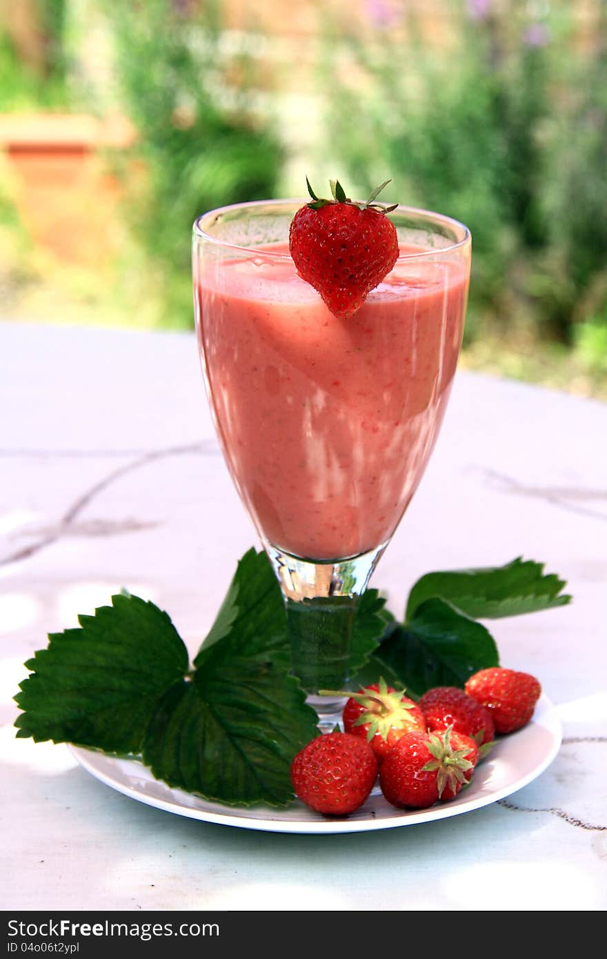 Image of a strawberry cut in half on a plat whit a strawberry drink. Image of a strawberry cut in half on a plat whit a strawberry drink