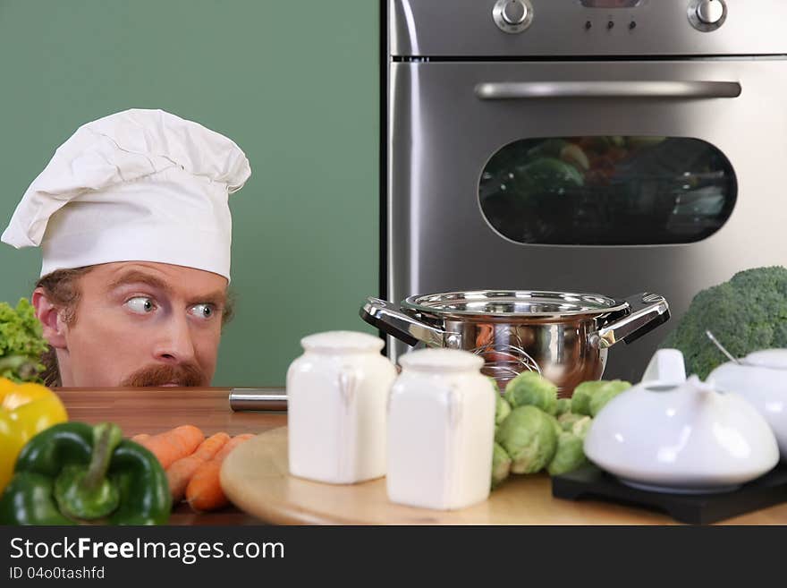 Funny young chef strange looking at pot