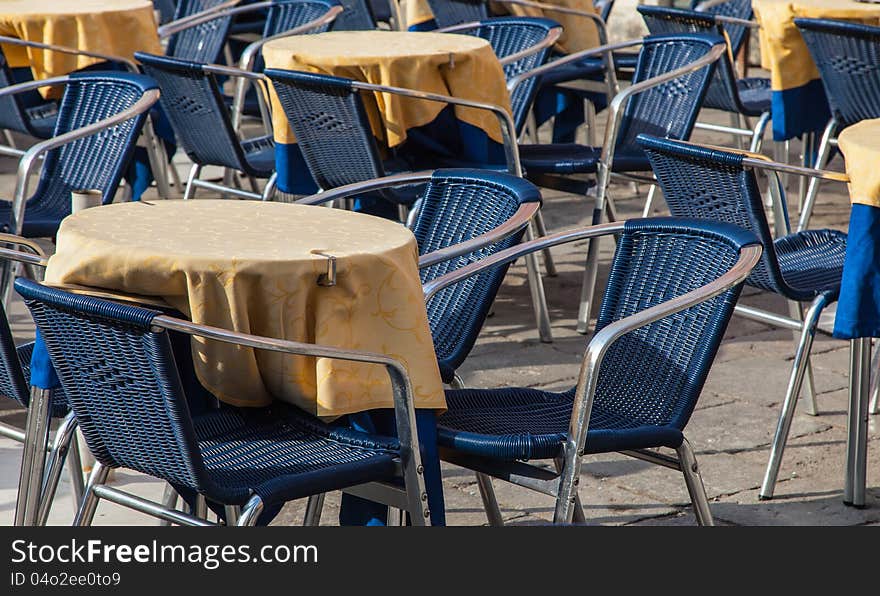 Image of a beautiful and bicolor Venetian street restaurant terrace with rattan chairs.