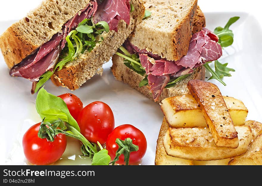 Pastrami filled sandwich with Salad and chips on a white plate. Studio shot. Pastrami filled sandwich with Salad and chips on a white plate. Studio shot