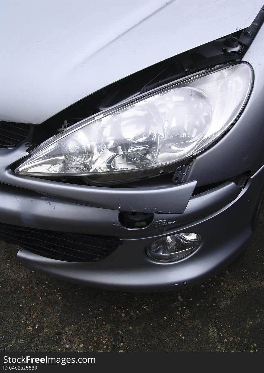 Damaged front of a grey car, on asphalt. Damaged front of a grey car, on asphalt.