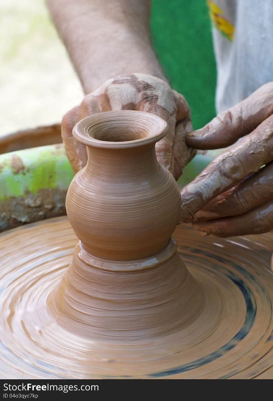 Hands of a potter, creating an earthen jar on the circle