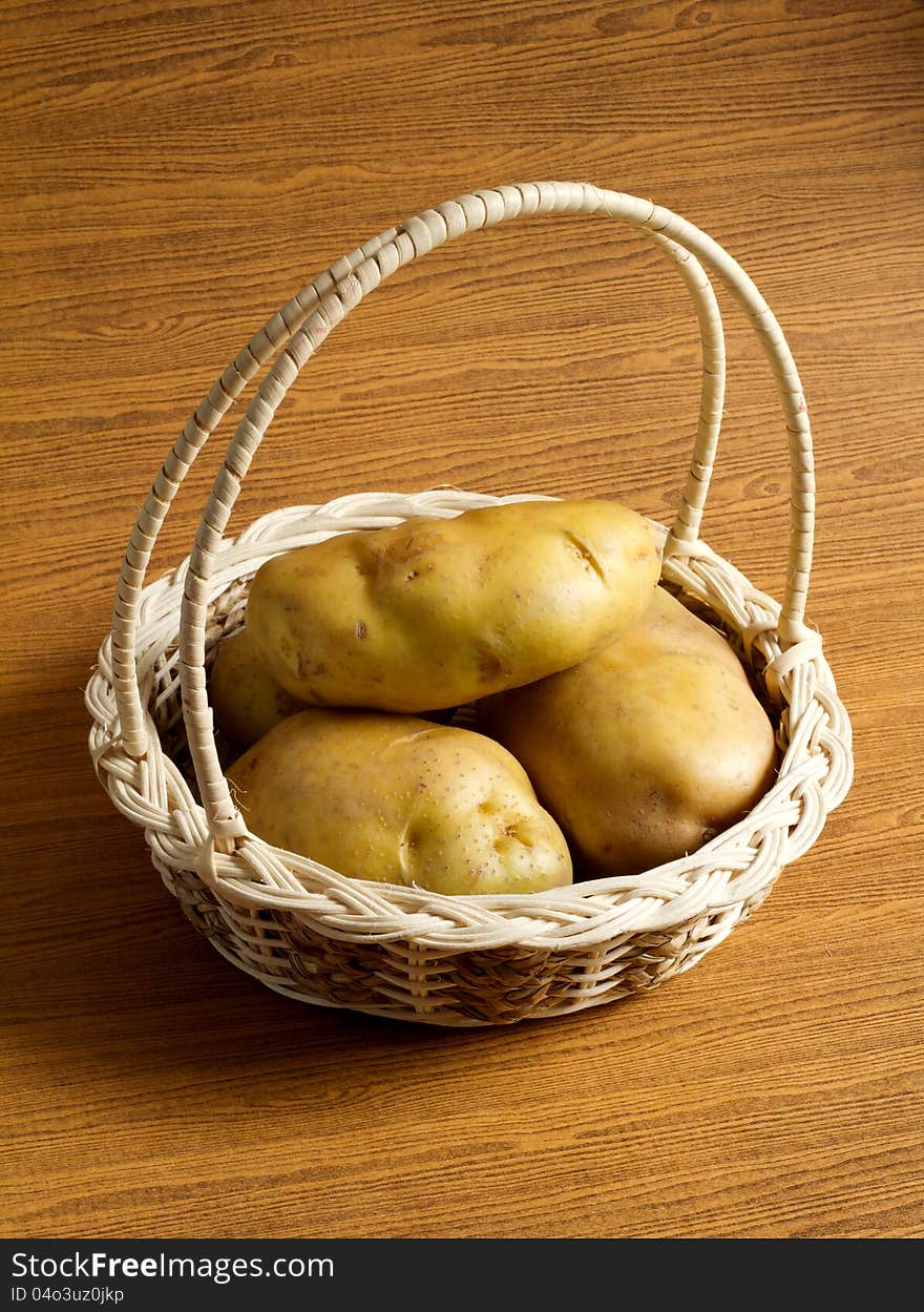 Potatos in the basket on the wood background. Potatos in the basket on the wood background