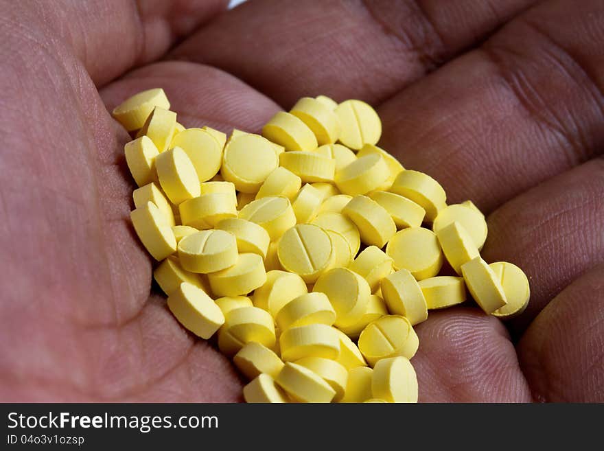 Small yellow pills in hand. Small yellow pills in hand