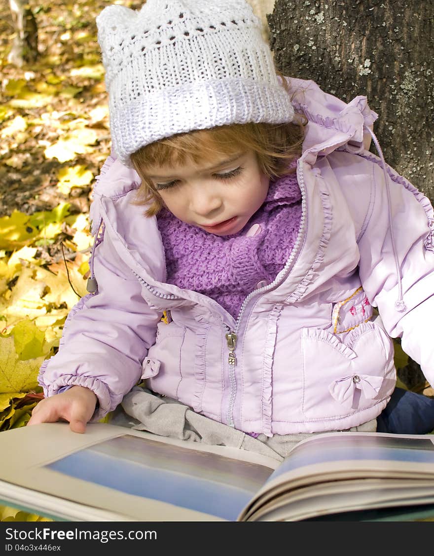 Girl reads a book in an autumn park