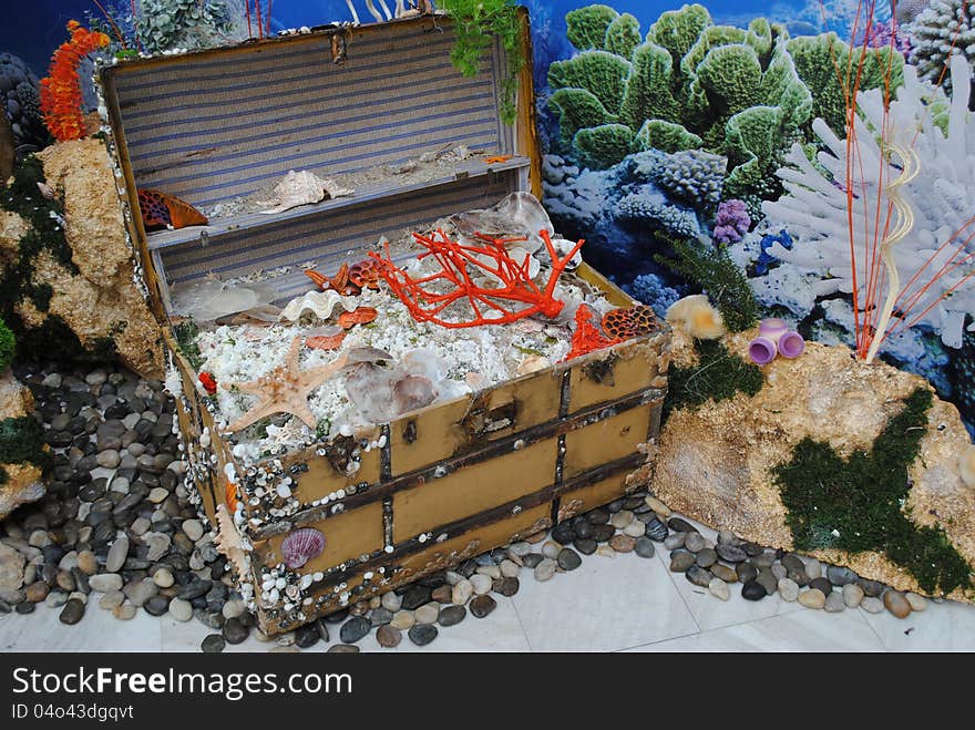 Trunk with treasure, starfishes, sea shels, pebbles against a background with sea and corals