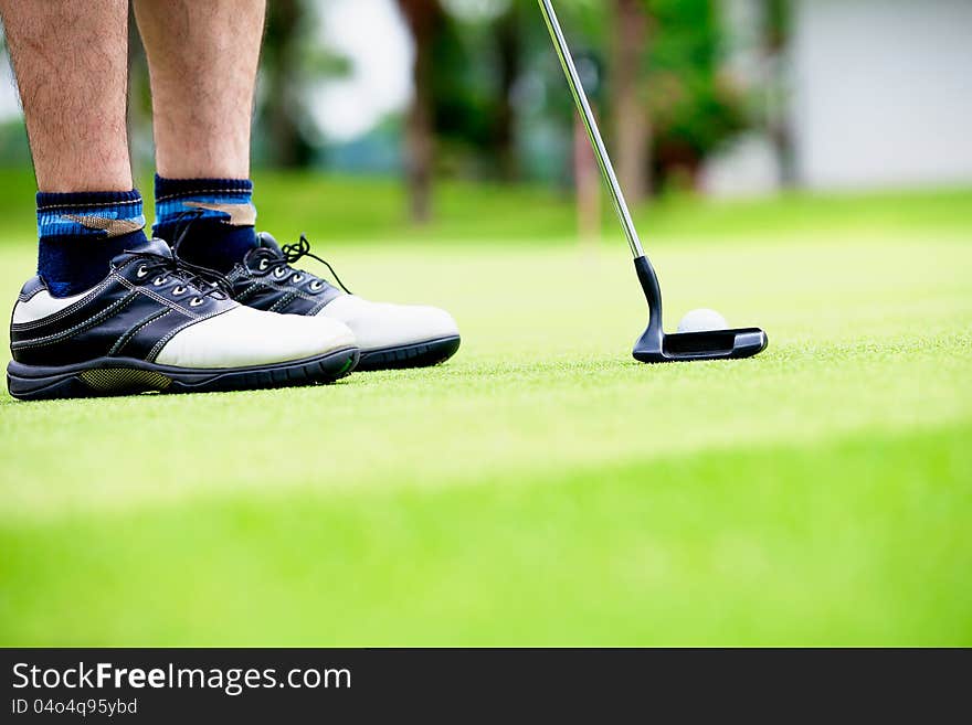 Golfer putting, selective focus on golf ball