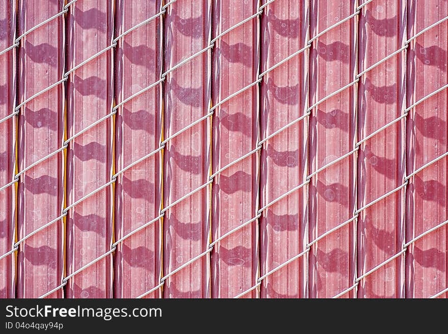 Closeup of pinkish chain link fence with barrier inserts. Closeup of pinkish chain link fence with barrier inserts.