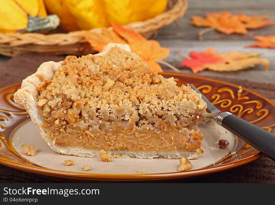 Slice of streusel pumpkin pie with autumn colors in background. Slice of streusel pumpkin pie with autumn colors in background