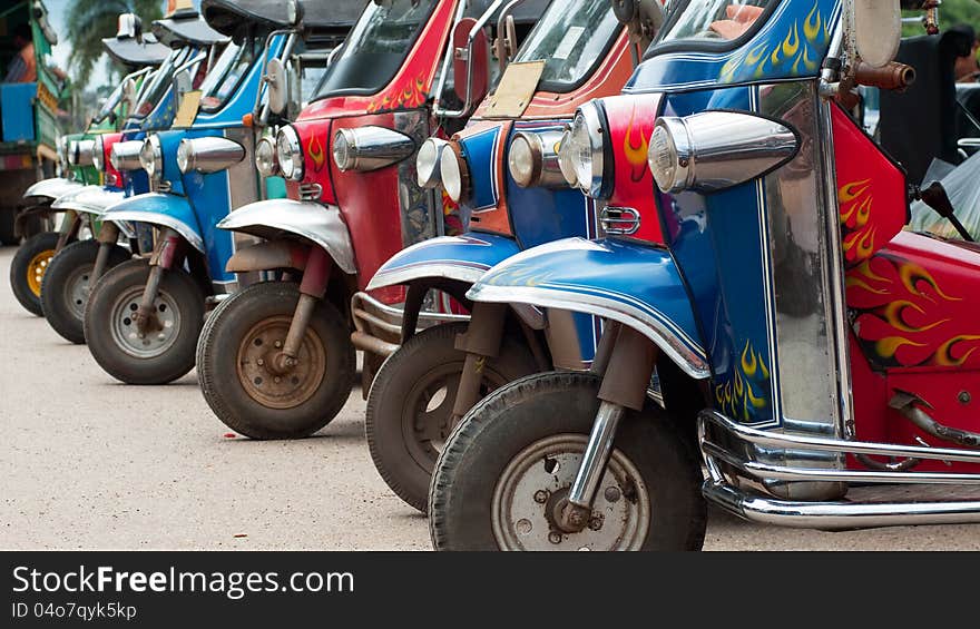 Old tuk-tuk taxis waiting for passengers in Thailand. This popular motorized transport has been in use in Thailand, almost unchanged, since the early nineteen fifties. Old tuk-tuk taxis waiting for passengers in Thailand. This popular motorized transport has been in use in Thailand, almost unchanged, since the early nineteen fifties.