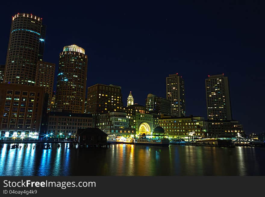 Boston skyline at night with part of the harbor in the foreground. Boston skyline at night with part of the harbor in the foreground