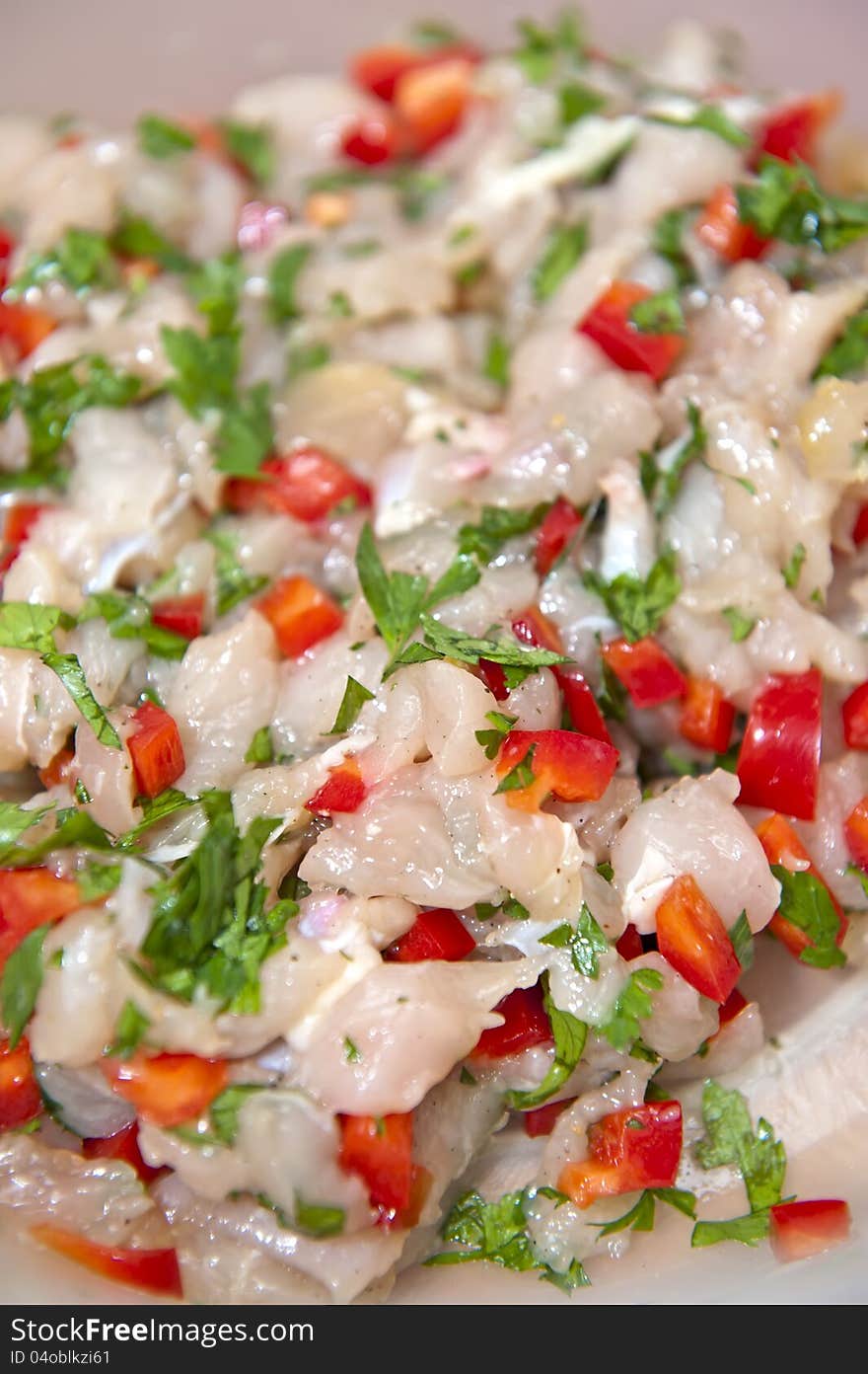 Close-up view of chopped raw chicken meat mixed with parsley and paprika. Mix for cutlets.