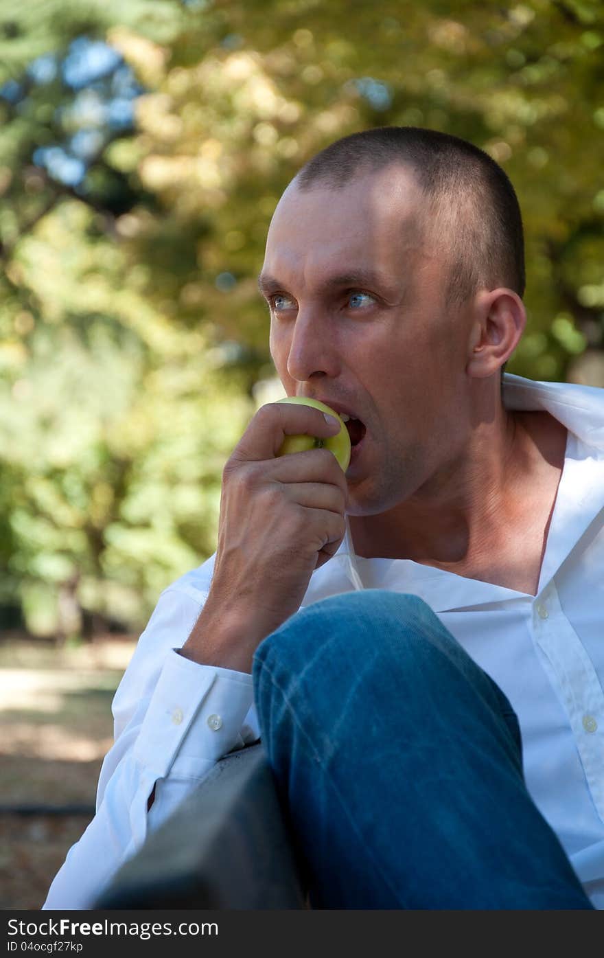 Man relaxing in the park and eating an apple